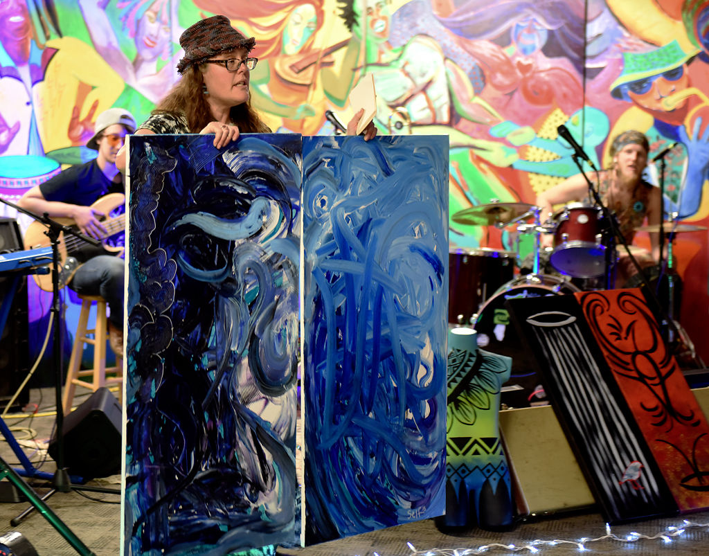 Stacy "Wildy" Self holds up a foldable painting at an auction